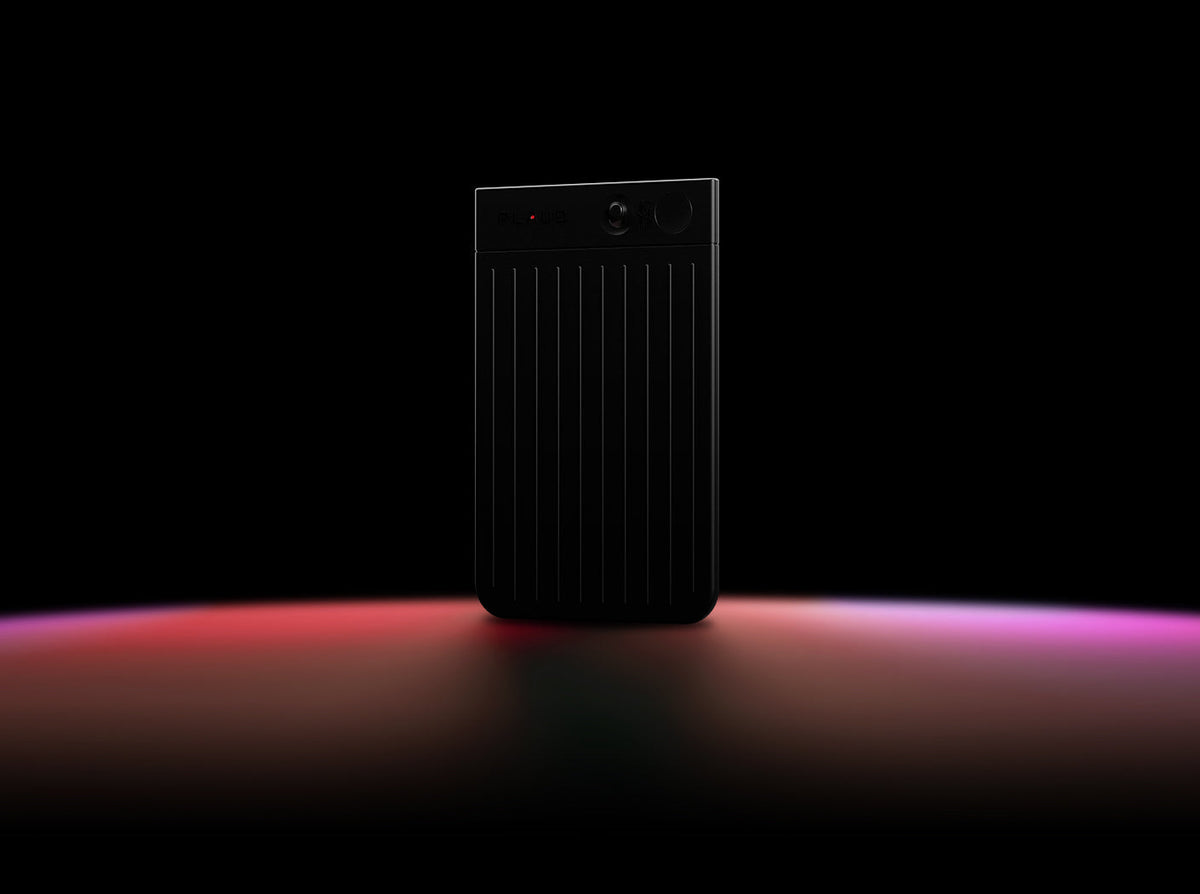 Un Plaud Note noir avec un voyant d'enregistrement rouge est posé sur une surface sombre