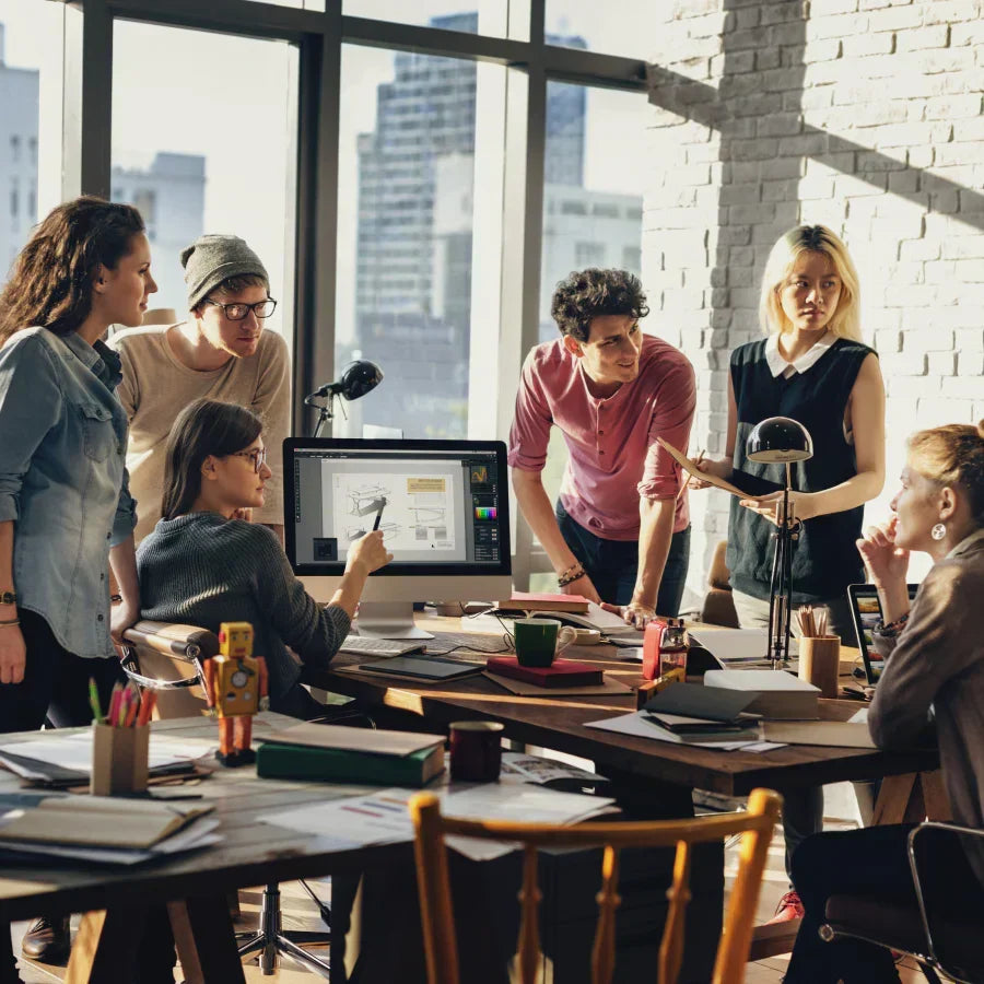 Un groupe de jeunes professionnels collabore autour d'un ordinateur dans un bureau moderne et lumineux.