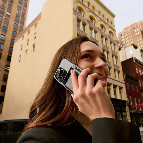 Femme souriante au téléphone dans la rue, utilisant la reconnaissance vocale sur Android.