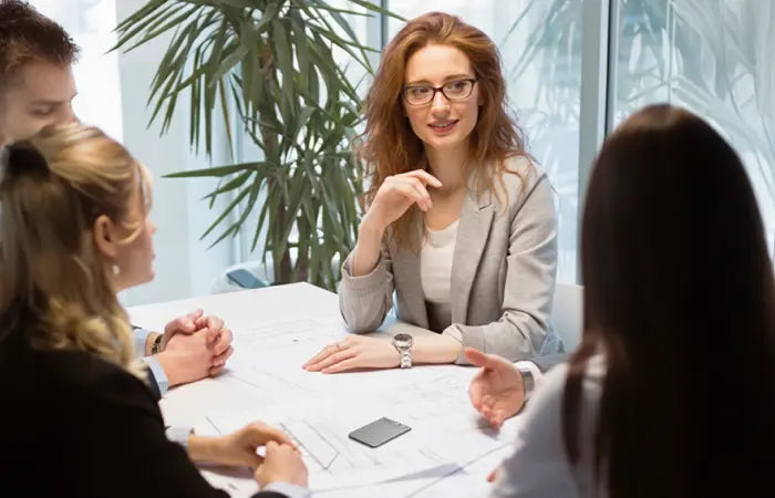 Quatre personnes en réunion autour d'une table avec un Plaud Note Pro noir posé sur des plans.