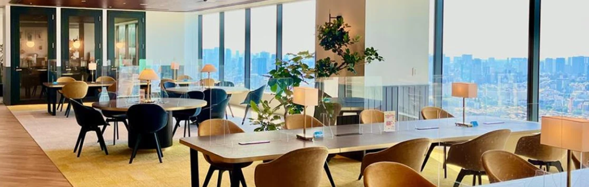 Un espace de travail moderne et lumineux avec des tables en bois, des chaises marron et noires, des plantes vertes.